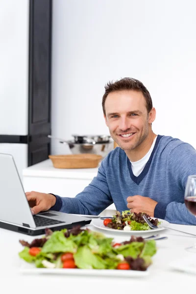 Fröhlicher Mann, der beim Mittagessen an seinem Laptop arbeitet — Stockfoto