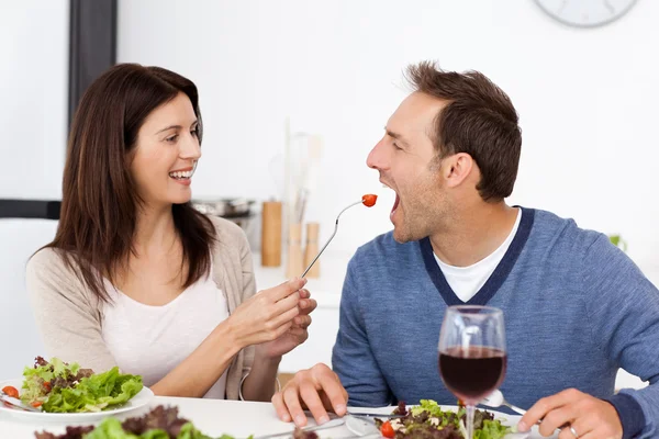 Pretty woman giving a tomato to her boyfriend while having lunch — Stock Photo, Image