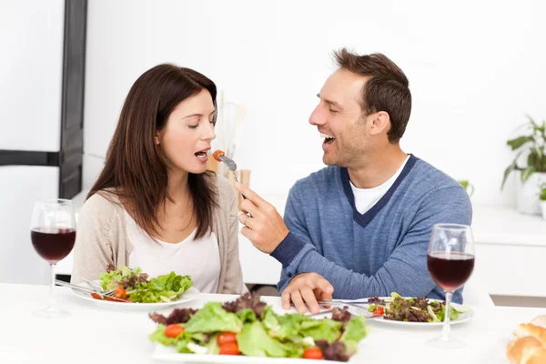 Attentive man giving a tomato to his girlfriend while having lu — Stock Photo, Image