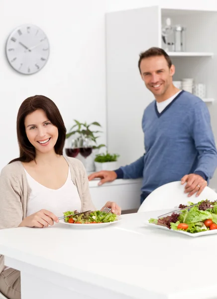 Happy couple eating a salad while drinking red wine — Stock Photo, Image