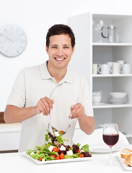 Щасливий чоловік змішуючи салат, що стоїть на кухні — стокове фото
