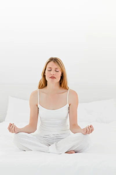 Frau praktiziert Yoga auf ihrem Bett — Stockfoto