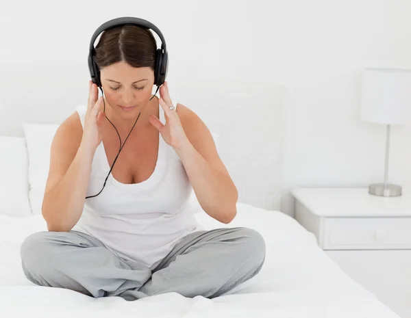Женщина слушает музыку на кровати — стоковое фото