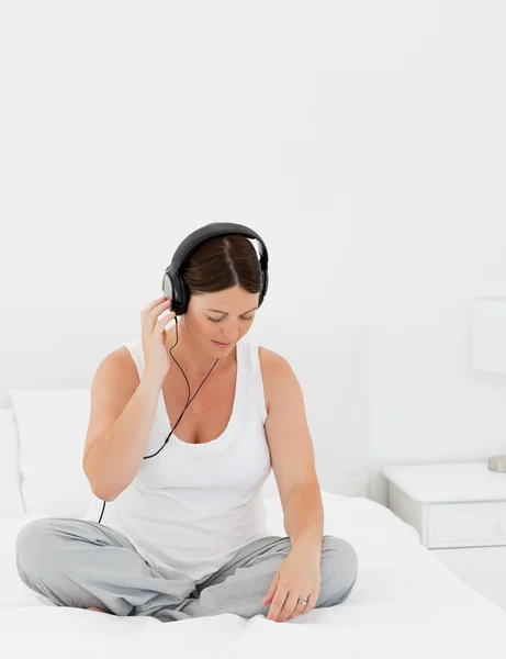 Kvinna lyssna på musik på sin säng — Stockfoto