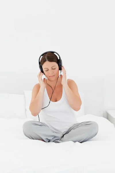 Słuchanie muzyki na jej łóżku kobieta — Zdjęcie stockowe