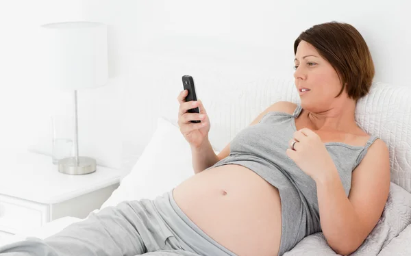 Schwangere blickt auf ihr Handy — Stockfoto