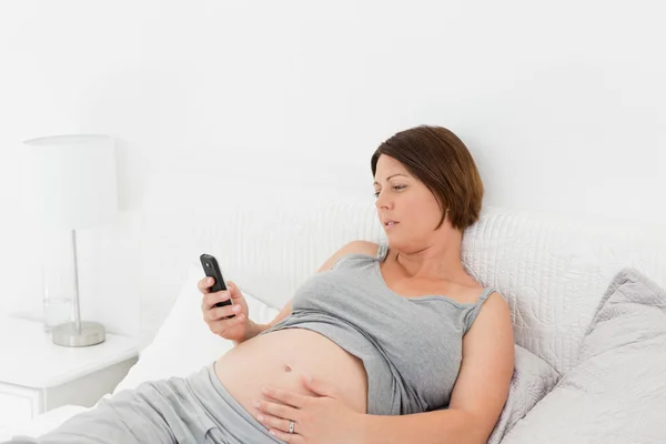 妊娠中の女性が彼女の携帯電話を見て — ストック写真