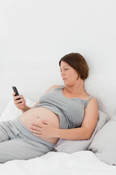 Mulher grávida olhando para o seu celular — Fotografia de Stock