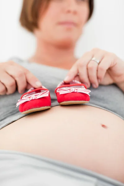 Kobieta w ciąży z buty dla dzieci — Zdjęcie stockowe