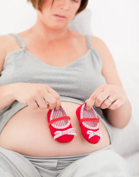 Mujer embarazada con zapatos de niños — Foto de Stock