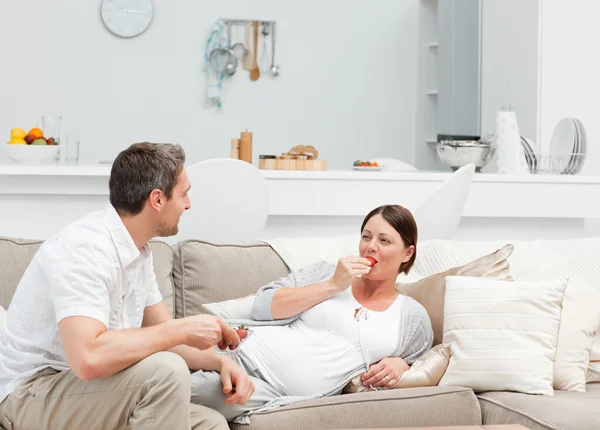 Беременная женщина с мужем, который ест клубнику — стоковое фото