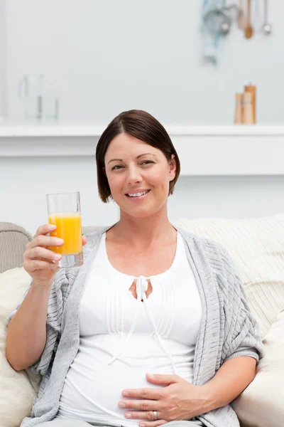 Kobieta w ciąży pije sok pomarańczowy — Zdjęcie stockowe