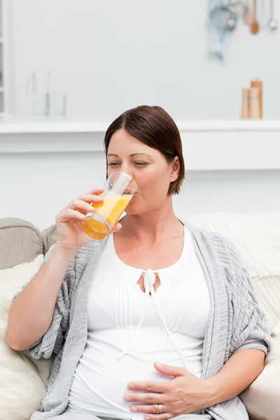 Těhotná žena pití šťávy oranje — Stock fotografie