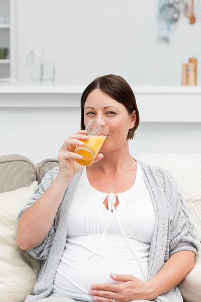 Беременная женщина пьет оранжевый сок — стоковое фото