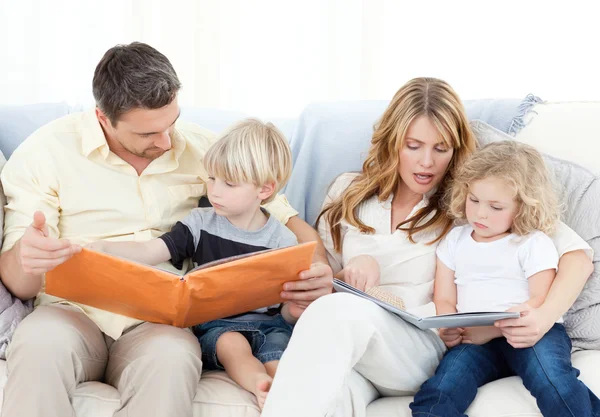 Семья читает книгу на диване — стоковое фото