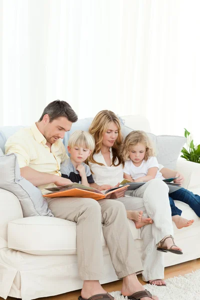 Семья читает книгу на диване — стоковое фото