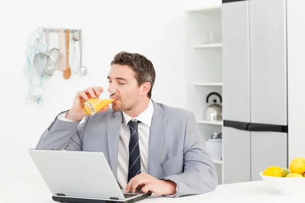 Affärsman dricka medan han tittar på sin laptop — Stockfoto
