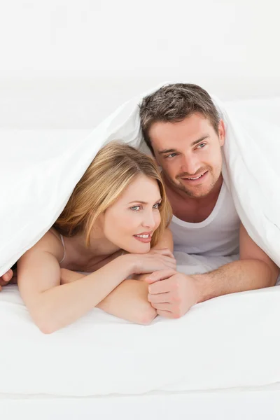 Schönes Paar, das sich in ihrem Bett umarmt — Stockfoto