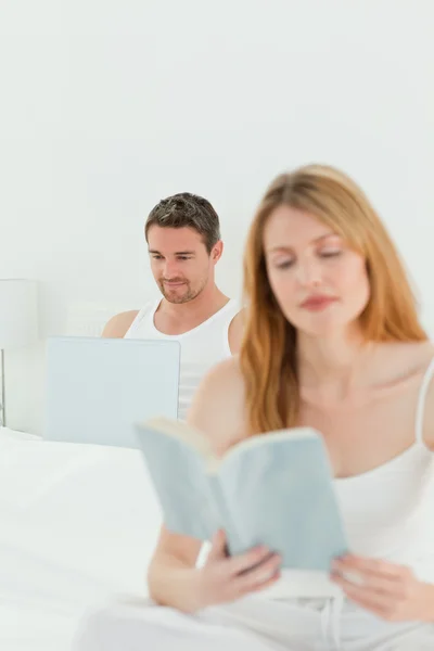 人是他的笔记本上，而他的妻子读一本书 — 图库照片