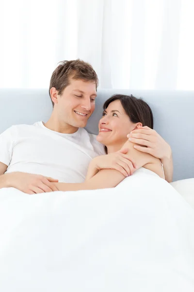 Uomo abbracciare la sua ragazza sul loro letto — Foto Stock