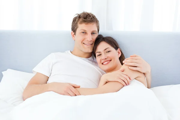 Człowiek przytulanie dziewczyną na swoim łóżku — Zdjęcie stockowe