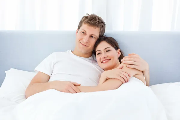 Мужчина обнимает свою девушку на их кровати — стоковое фото