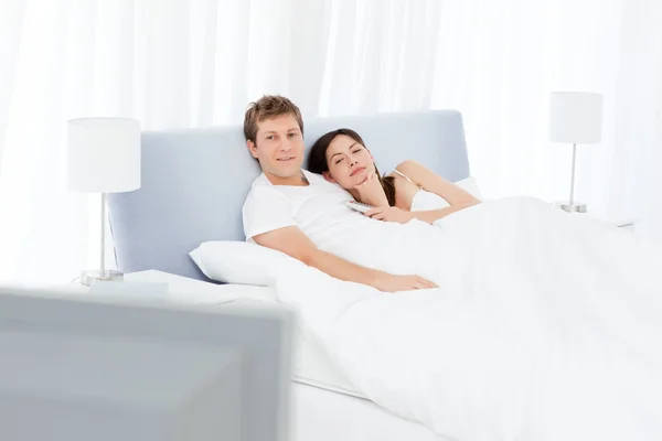 Пара смотрит телевизор в своей постели — стоковое фото