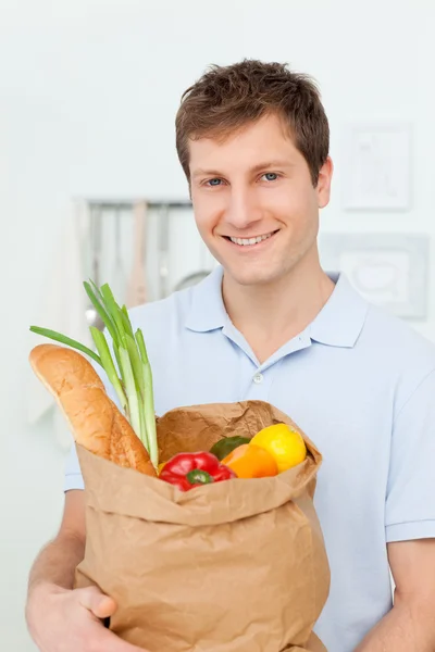 Muž s nákupní tašky v kuchyni — Stock fotografie