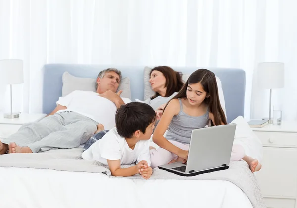 Barn ser på sin laptop medan föräldrar talar — Stockfoto