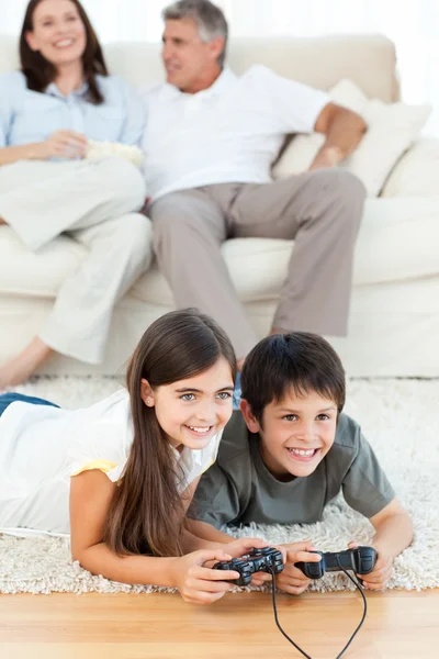 Crianças jogando videogames enquanto os pais estão falando — Fotografia de Stock