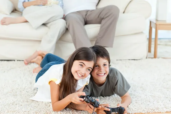 Niños jugando videojuegos mientras los padres están hablando — Foto de Stock