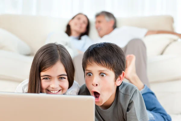 Crianças encantadoras assistindo a um filme em seu laptop em casa — Fotografia de Stock