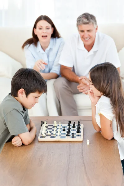 Parents looking their children playing chess — Stock Photo, Image