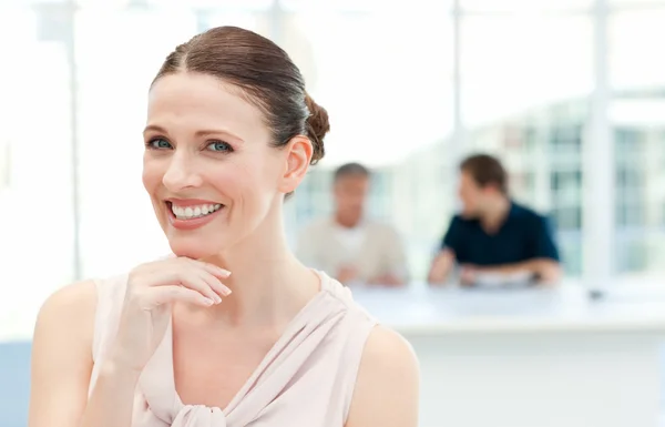 Mujer de negocios sonriente mirando a la cámara mientras sus compañeros de trabajo — Foto de Stock