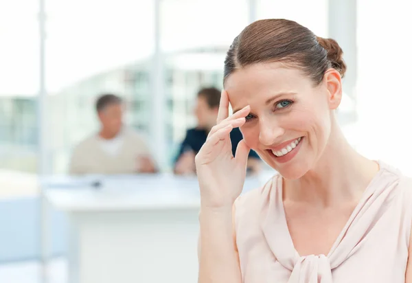 Lächelnde Geschäftsfrau blickt in die Kamera, während ihre Mitarbeiter — Stockfoto