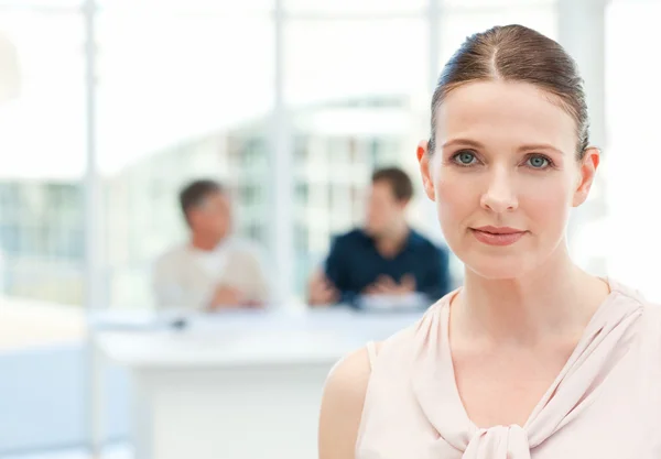 Serious businesswoman looking at the camera while her coworkers — Stock Photo, Image