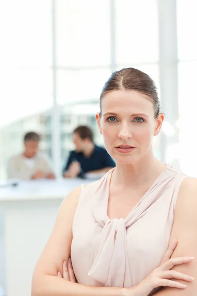Seriöse Geschäftsfrau blickt in die Kamera, während ihre Mitarbeiter — Stockfoto