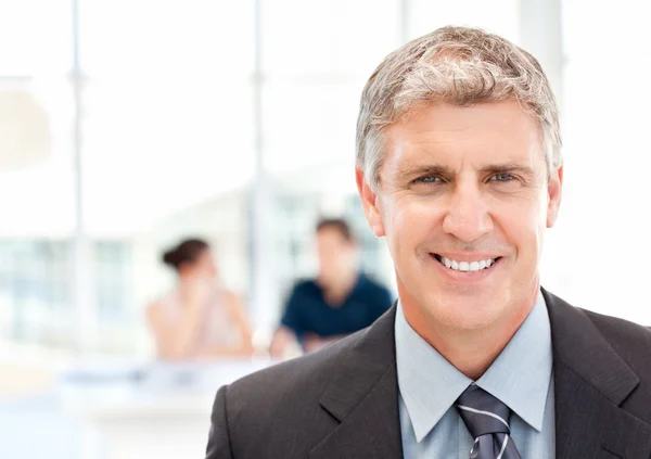 Businessman looking at the camera while their team is working — Stock Photo, Image