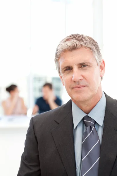 Businessman looking at the camera while his team is working — Stock Photo, Image