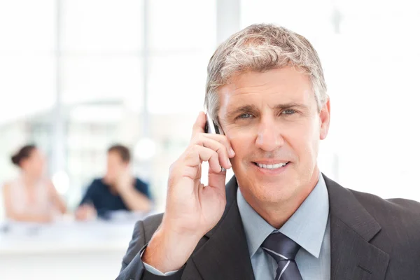 Empresário telefonando enquanto sua equipe está trabalhando — Fotografia de Stock