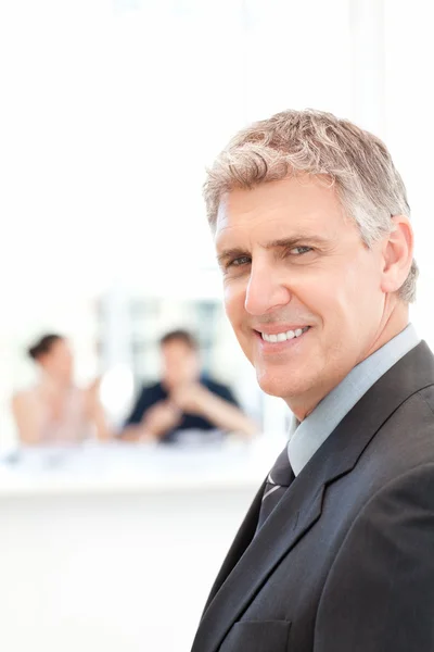 Businessman looking at the camera while his team is working — Stock Photo, Image