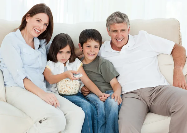 Familia viendo televisión mientras comen palomitas de maíz —  Fotos de Stock