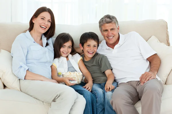 Семья смотрит телевизор, пока они едят попкорн — стоковое фото