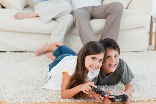 Gyermekek játszanak a videojátékok, míg a szülők beszélgetnek — Stock Fotó
