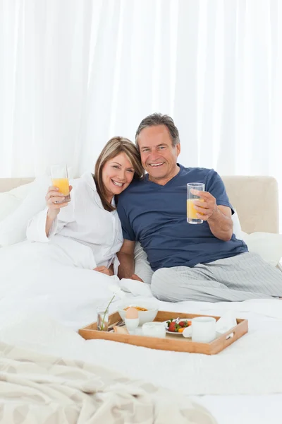 Charmant couple prenant le petit déjeuner dans leur lit — Photo