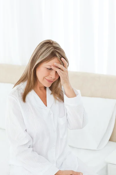 Vrouw met een hoofdpijn op haar bed — Stockfoto
