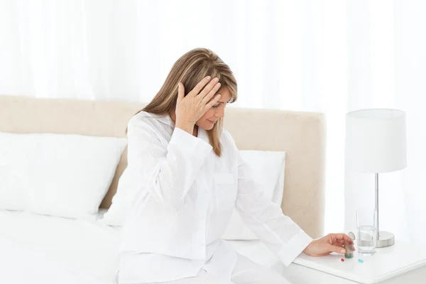 Kobieta o ból głowy na jej łóżko — Zdjęcie stockowe