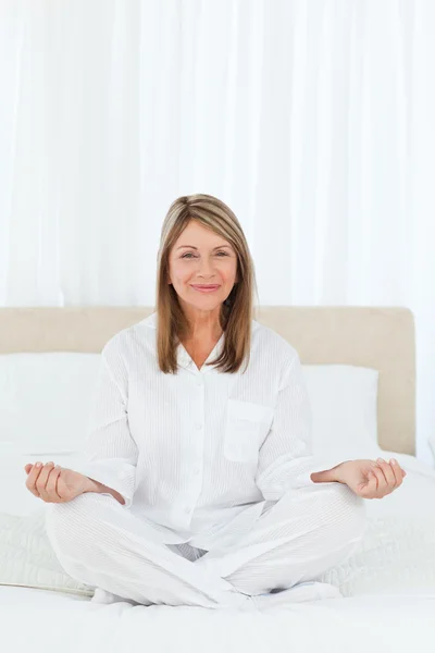 Senior utövar yoga på hennes säng — Stockfoto