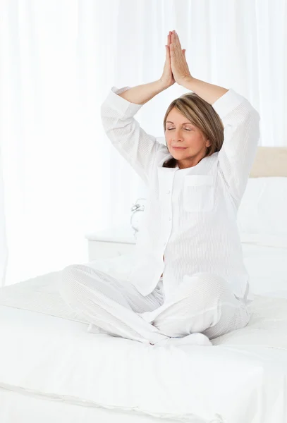 Senior praktiserende yoga på hendes seng - Stock-foto