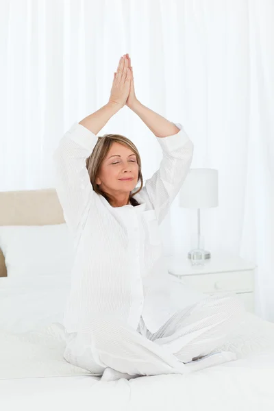 Senior praticare yoga sul suo letto — Foto Stock